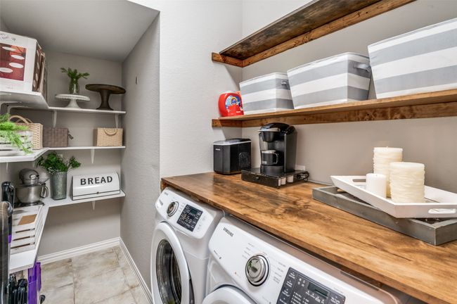 Laundry room with washing machine and dryer and shelving for all your additional storage needs! Love the folding area too! | Image 31