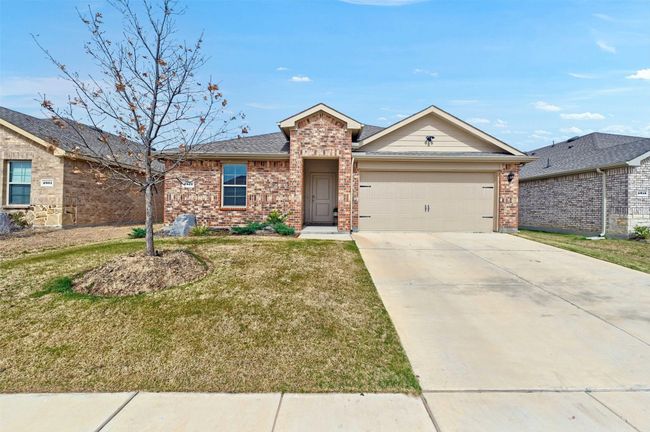 View of front of home with brick siding, a garage, concrete driveway, and a front lawn | Image 4