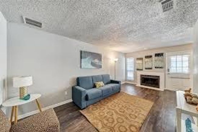 Living room with visible vents, a fireplace with raised hearth, baseboards, wood finished floors, and a textured ceiling | Image 7