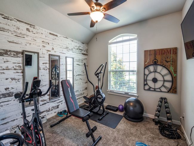 Exercise room featuring ceiling fan, baseboards, carpet flooring, and vaulted ceiling | Image 28