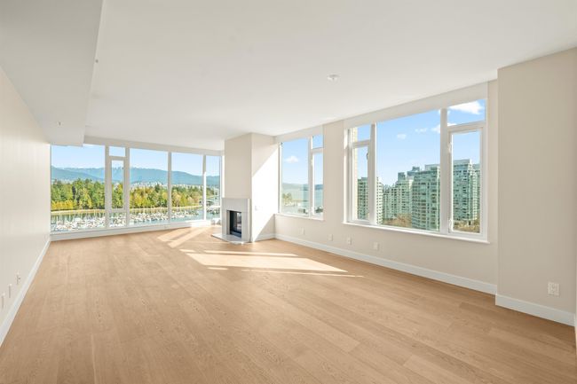 Unfurnished living room featuring a view of city, light wood-style floors, a glass covered fireplace, a mountain view, and baseboards | Image 4