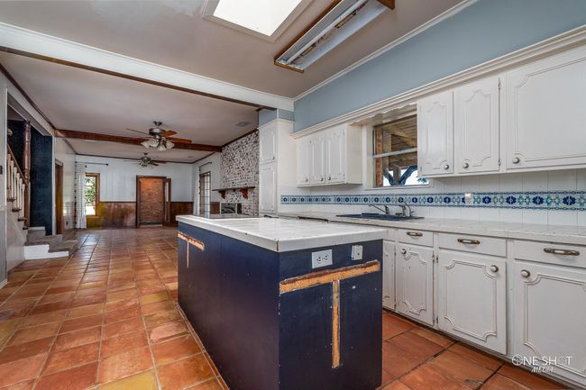 Kitchen with a center island, sink, white cabinetry, crown molding, and ceiling fan | Image 11