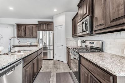 Kitchen with appliances with stainless steel finishes, light stone countertops, light hardwood / wood-style floors, sink, and tasteful backsplash | Image 3