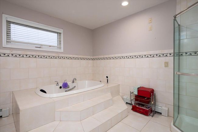 Full bathroom with tile walls, a bath, tile patterned flooring, a shower stall, and a baseboard radiator | Image 23