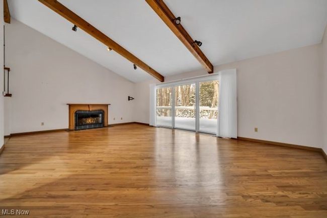 Unfurnished living room with light wood-type flooring, high vaulted ceiling, and beam ceiling | Image 11