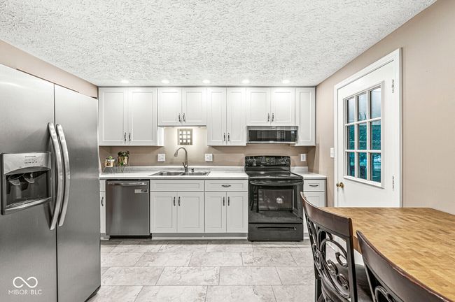 kitchen featuring stainless steel appliances, light countertops, a textured ceiling, and recessed lighting | Image 5