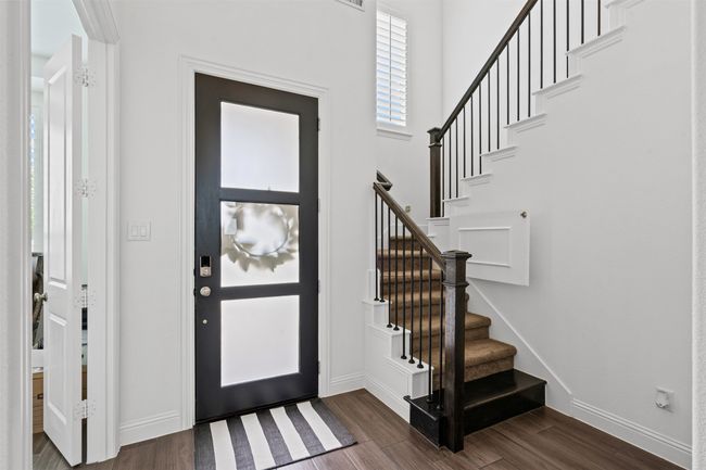 Entrance foyer with dark wood-style flooring, baseboards, stairway, and a high ceiling | Image 7