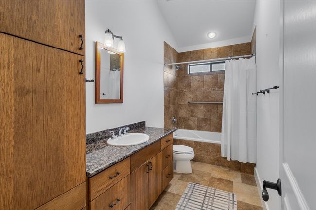 Bathroom featuring stone finish floor, vanity, and tiled shower / bath | Image 24