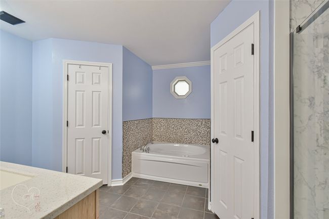 Bathroom featuring vanity, a bath, tile patterned flooring, and a marble finish shower | Image 24