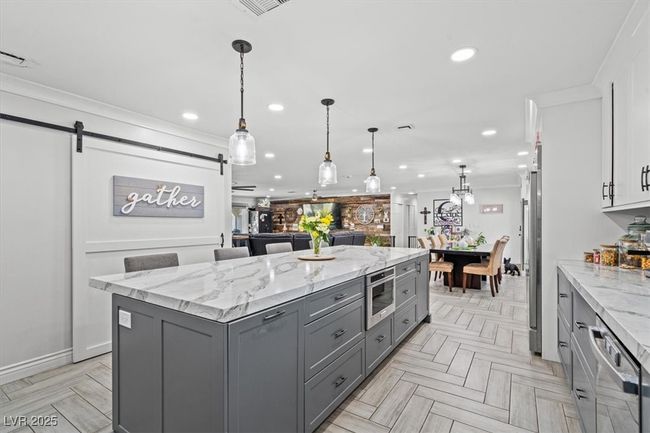 Kitchen with a barn door, a kitchen island, ornamental molding, and gray cabinetry | Image 7