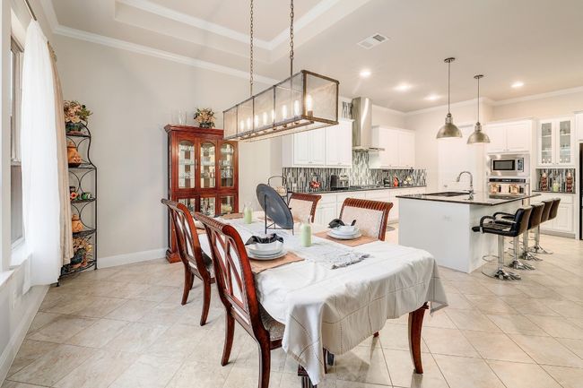 Dining space with crown molding, light tile patterned floors, a tray ceiling, and recessed lighting | Image 8
