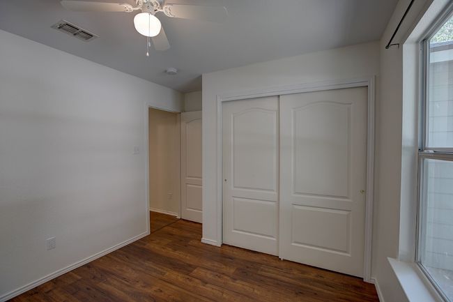 Unfurnished bedroom with dark wood-type flooring, a closet, ceiling fan, and baseboards | Image 37
