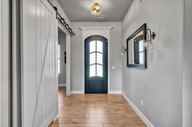 Foyer featuring a barn door, light wood finished floors, and baseboards | Image 13