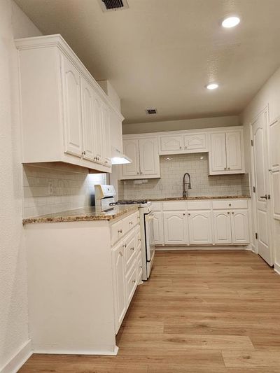 Kitchen featuring white stove, light hardwood / wood-style floors, and white cabinets | Image 3