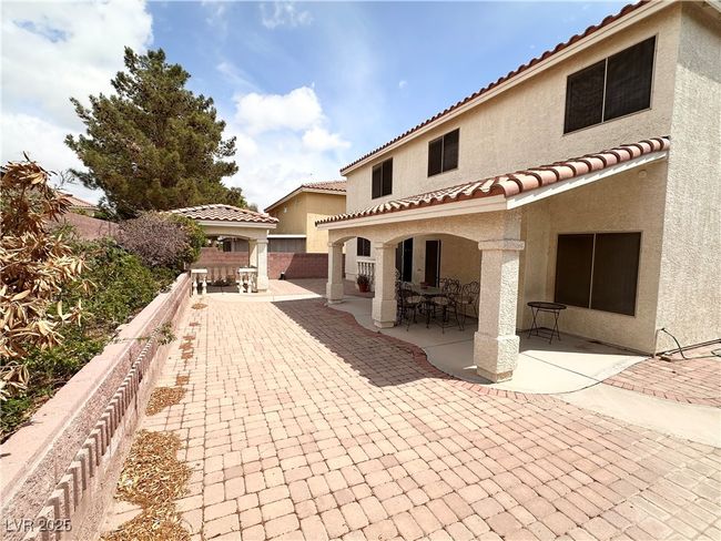 Back of property with stucco siding, a patio, a fenced backyard, a tile roof, and outdoor dining area | Image 27