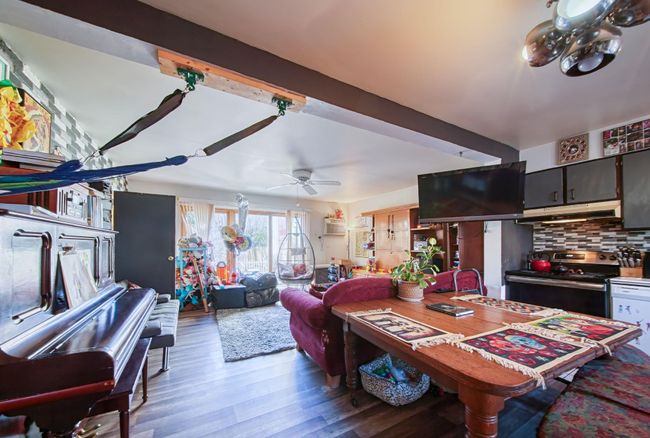 Living room with a ceiling fan, a wall unit AC, beamed ceiling, and wood finished floors | Image 4
