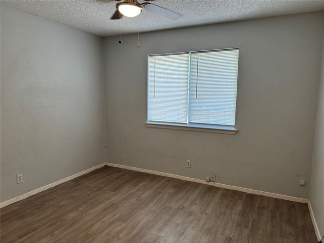 Empty room with wood finished floors, a textured ceiling, and a ceiling fan | Image 8