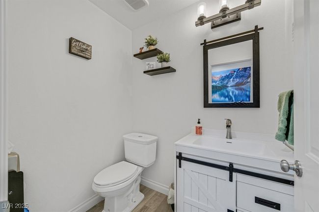 Half bathroom featuring baseboards, toilet, wood finished floors, and vanity | Image 24