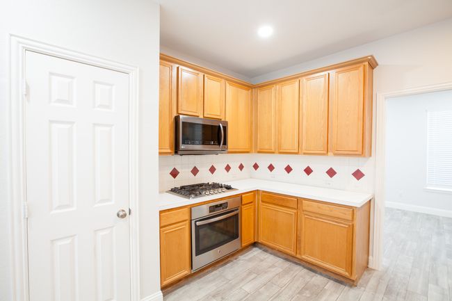 Kitchen with appliances with stainless steel finishes, light countertops, tasteful backsplash, light wood finished floors, and recessed lighting | Image 10