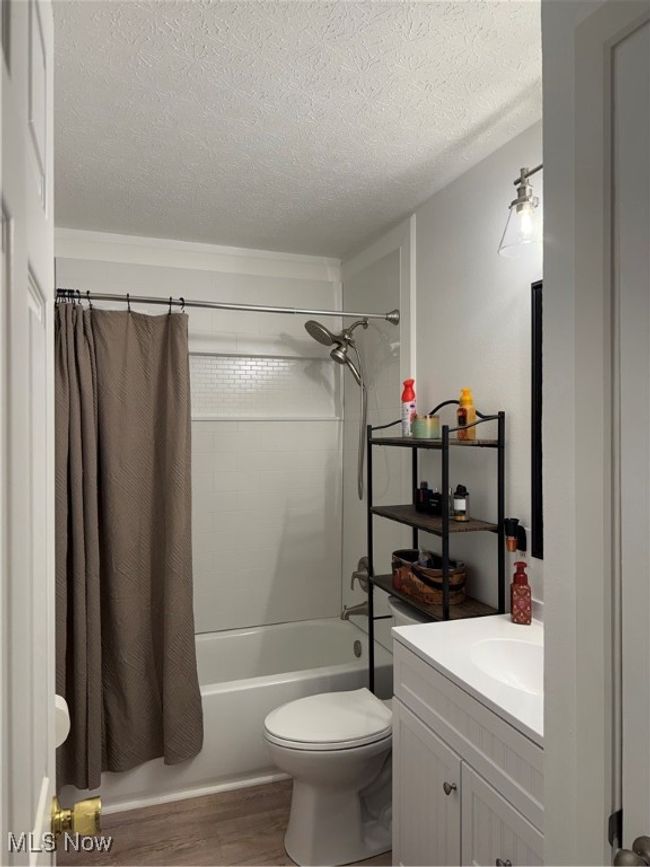 Full bath with wood finished floors, toilet, vanity, a textured ceiling, and shower / bath combo | Image 17