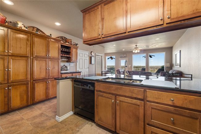 Kitchen with brown cabinetry, recessed lighting, dishwasher, and open shelves | Image 12