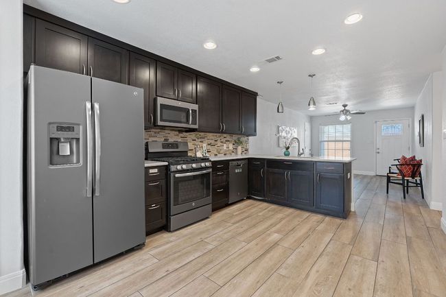 Kitchen with appliances with stainless steel finishes, a peninsula, light countertops, light wood-style floors, and a ceiling fan | Image 4