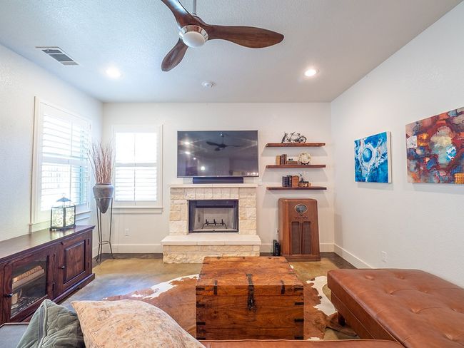Living area featuring a stone fireplace, ceiling fan, finished concrete flooring, recessed lighting, and a textured ceiling | Image 12
