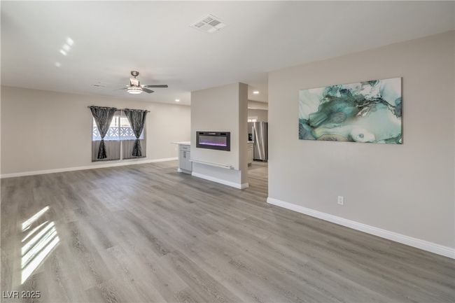 Unfurnished living room featuring light wood finished floors, a ceiling fan, visible vents, and baseboards | Image 6