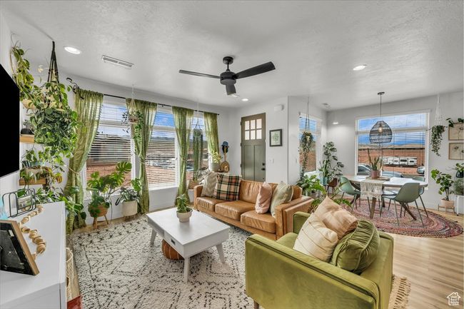 Living room featuring wood finished floors, a textured ceiling, ceiling fan, and visible vents | Image 6