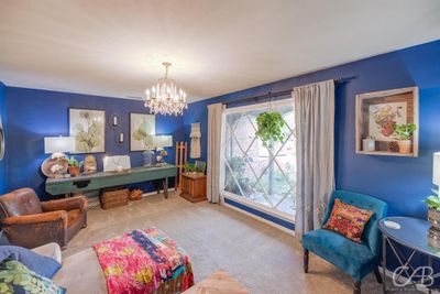 Living area featuring light colored carpet and a notable chandelier | Image 3