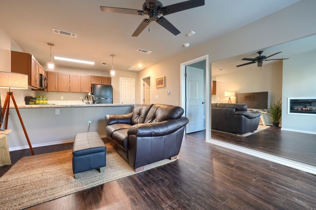 Living room with a ceiling fan, visible vents, and dark wood-style flooring | Image 7