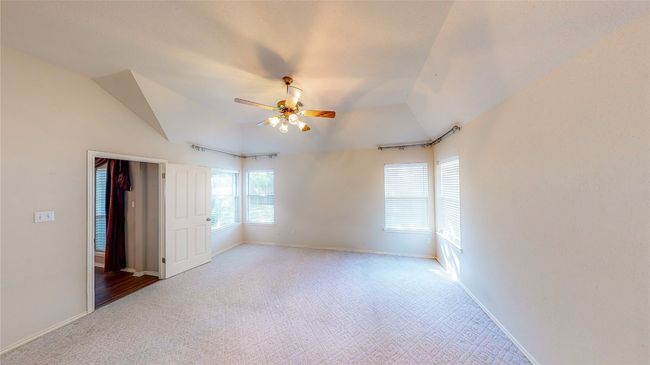 Unfurnished bedroom with carpet, vaulted ceiling, and a ceiling fan | Image 5