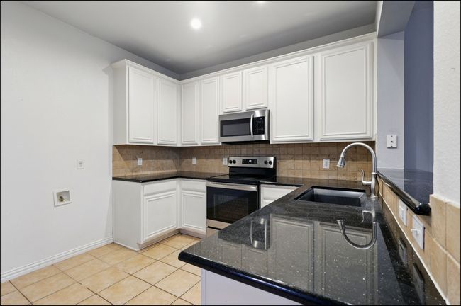 Kitchen featuring white cabinetry, appliances with stainless steel finishes, decorative backsplash, and a sink | Image 10