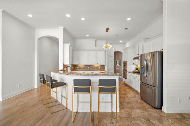 The kitchen impresses with elegant granite countertops, ample stainless steel appliances, and a spacious walk-in pantry. Featuring expansive cabinetry and a breakfast bar, it offers a blend of modern convenience and comfort. Ideal for culinary endeavors, this space is both functional and inviting. | Image 15