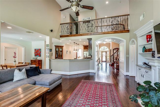 Huge Living Room with Hardwood floors, high ceilings, gas log fire, beautiful wrought iron staircase, built in shlves, open though to the kitchen | Image 12