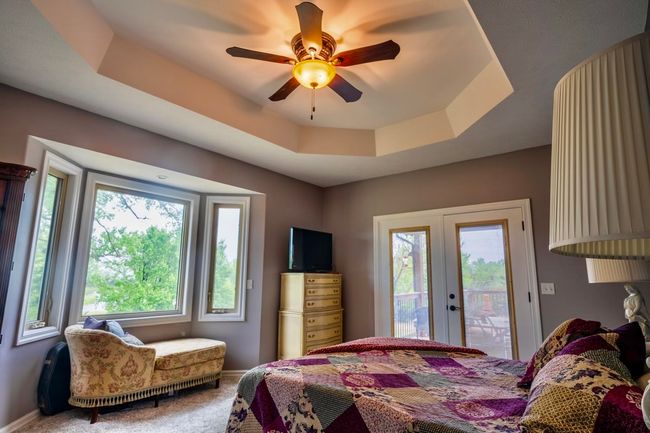 Bedroom featuring access to outside, a tray ceiling, multiple windows, and french doors | Image 18