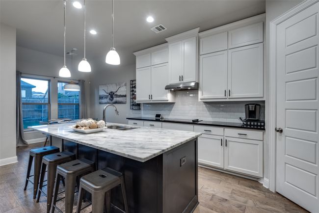 Kitchen with a sink, tasteful backsplash, a center island with sink, visible vents, and under cabinet range hood | Image 6
