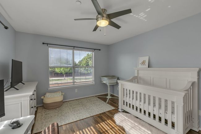 Bedroom with wood finished floors, a crib, and a ceiling fan | Image 23