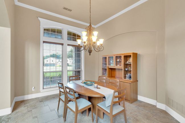 Dining space featuring stone tile floors, a chandelier, and crown molding | Image 11