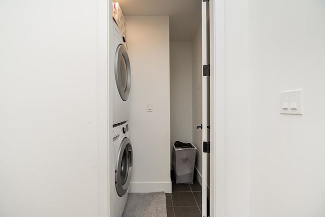 Laundry room featuring stacked washer / drying machine and dark tile patterned flooring | Image 28