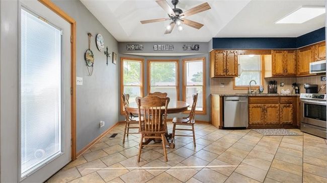 Kitchen featuring appliances with stainless steel finishes, brown cabinetry, backsplash, a ceiling fan, and light countertops | Image 7