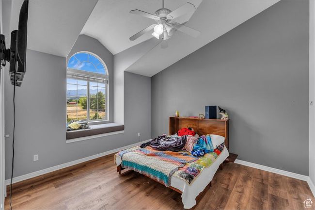 Bedroom with lofted ceiling, a ceiling fan, baseboards, and wood finished floors | Image 23