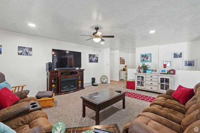 Carpeted living room with recessed lighting, a textured ceiling, and a ceiling fan | Image 11