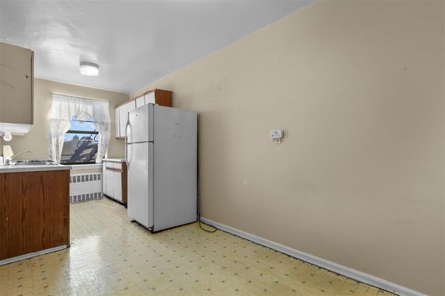 Kitchen with freestanding refrigerator, radiator, light flooring, and light countertops | Image 5