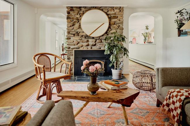 Living area with baseboard heating, arched walkways, wood finished floors, and a stone fireplace | Image 8