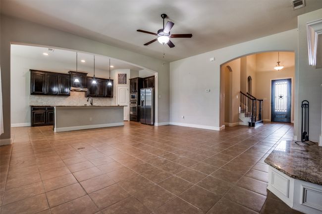 Unfurnished living room featuring a ceiling fan, dark tile patterned flooring, stairway, recessed lighting, and arched walkways | Image 5