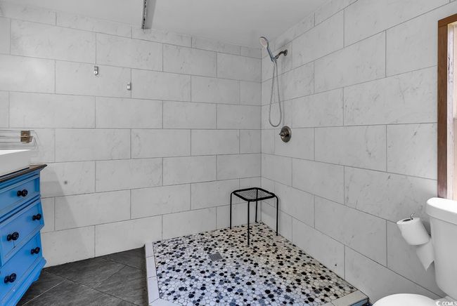 Full bath featuring double vanity, a tile shower, and tile walls | Image 16
