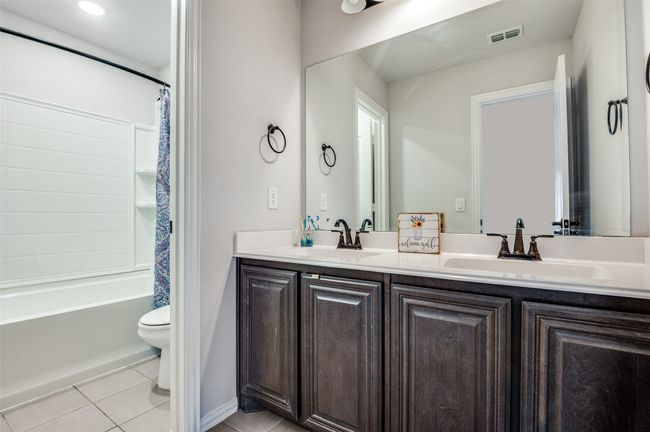 Bathroom with double vanity, tile patterned floors, and shower / tub combo with curtain | Image 23