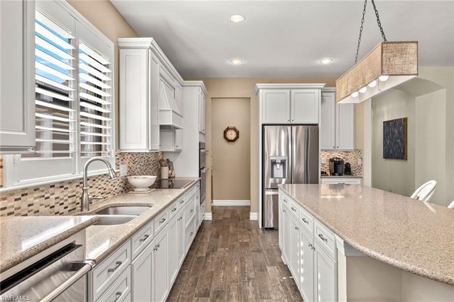 Kitchen featuring light stone countertops, backsplash, pendant lighting, white cabinets, and appliances with stainless steel finishes | Image 9
