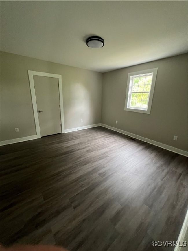 Spare room featuring baseboards and dark wood-type flooring | Image 23